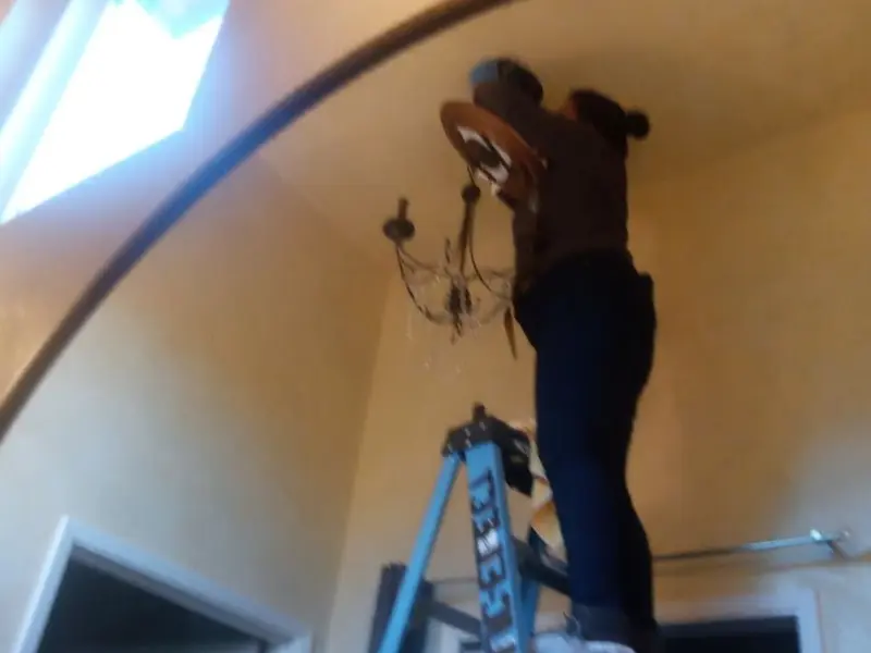 Electrician installing a chandelier in a Mehlville residence